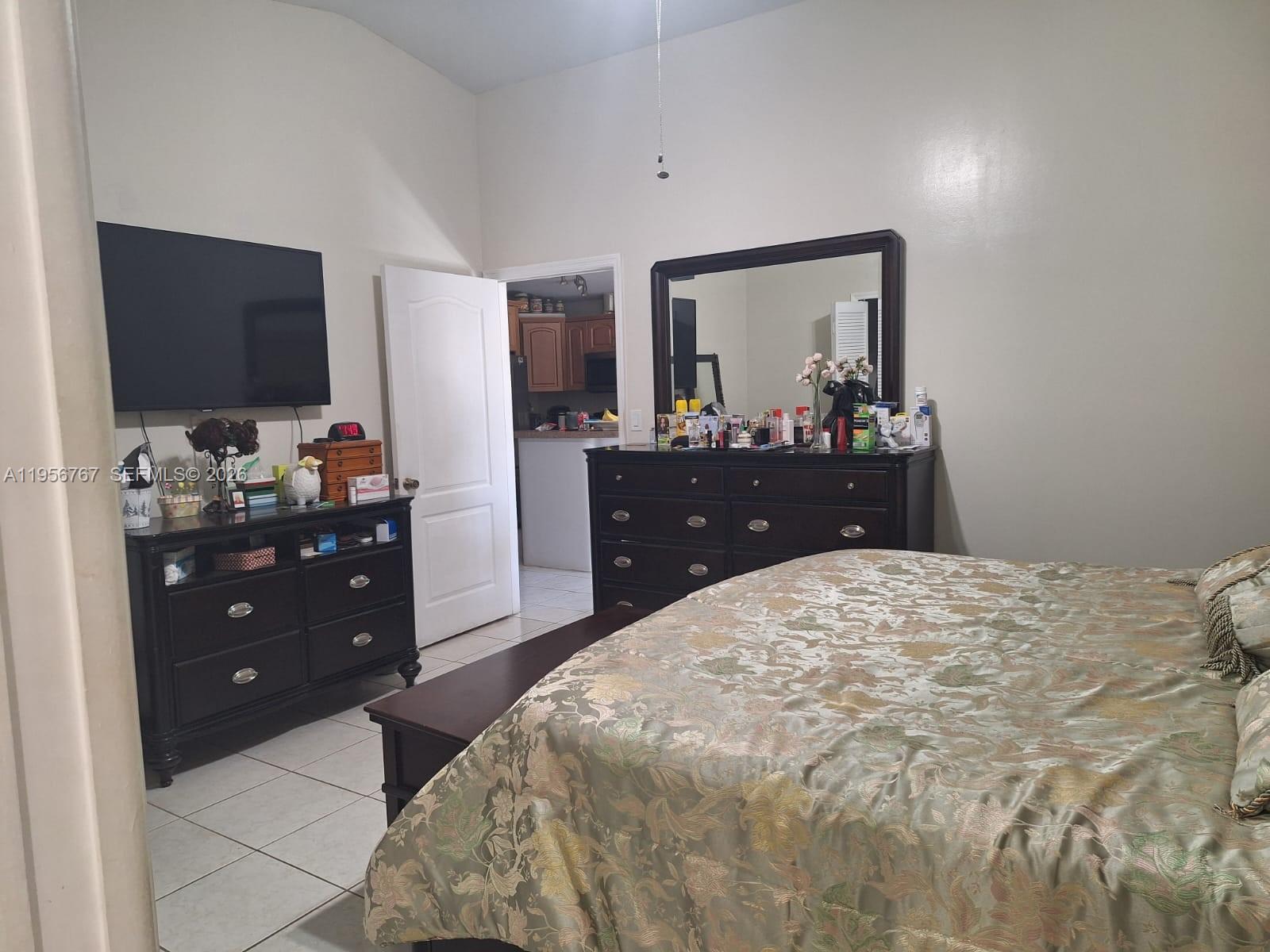 A bedroom features a bed with a patterned comforter, two dark dressers, and a doorway — 13822 SW 156th St, Miami FL 33177, MIAMI, FL