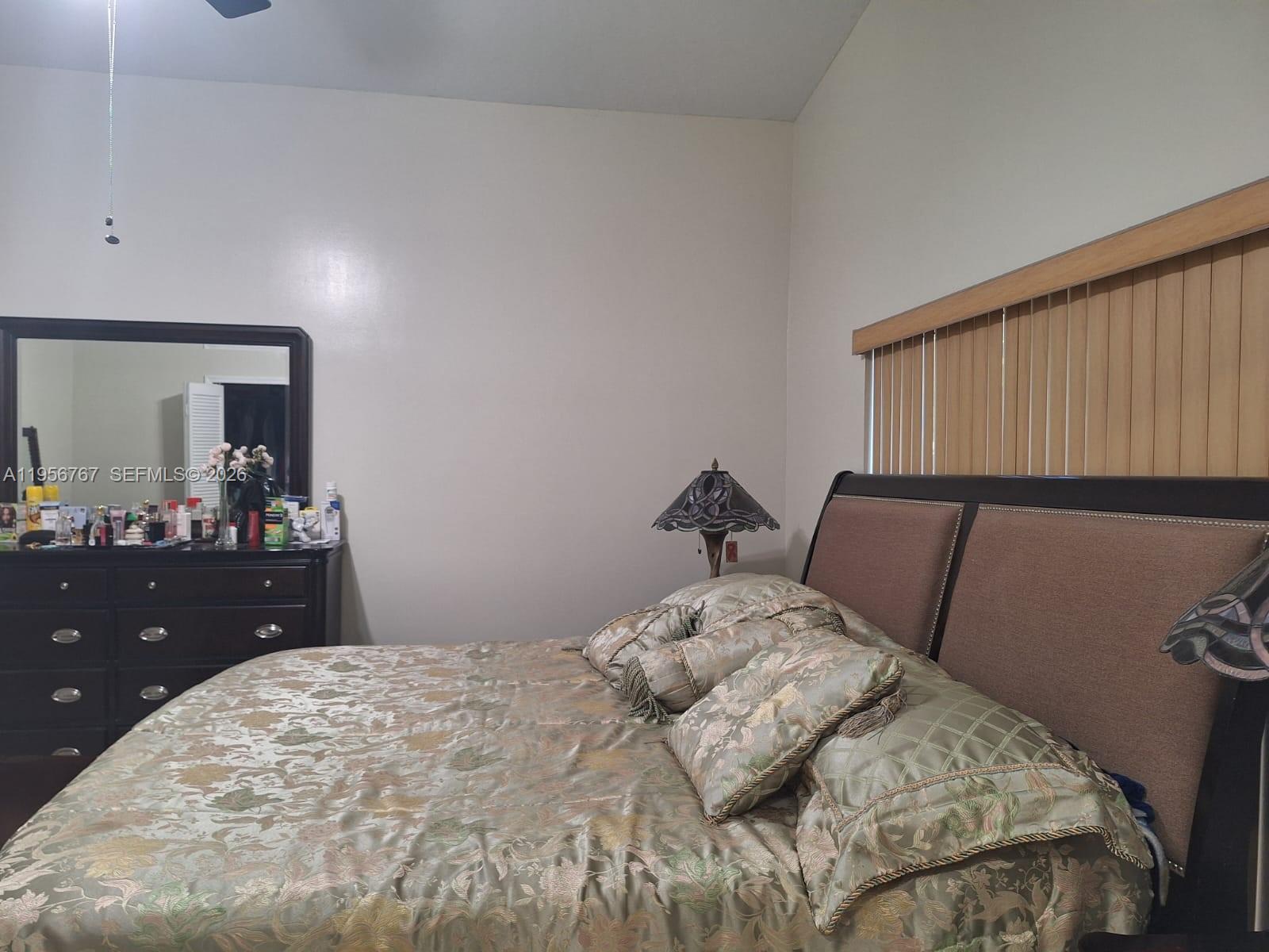 A bedroom features a dark wood bed frame, a matching dresser with a mirror, and bedding — 13822 SW 156th St, Miami FL 33177, MIAMI, FL