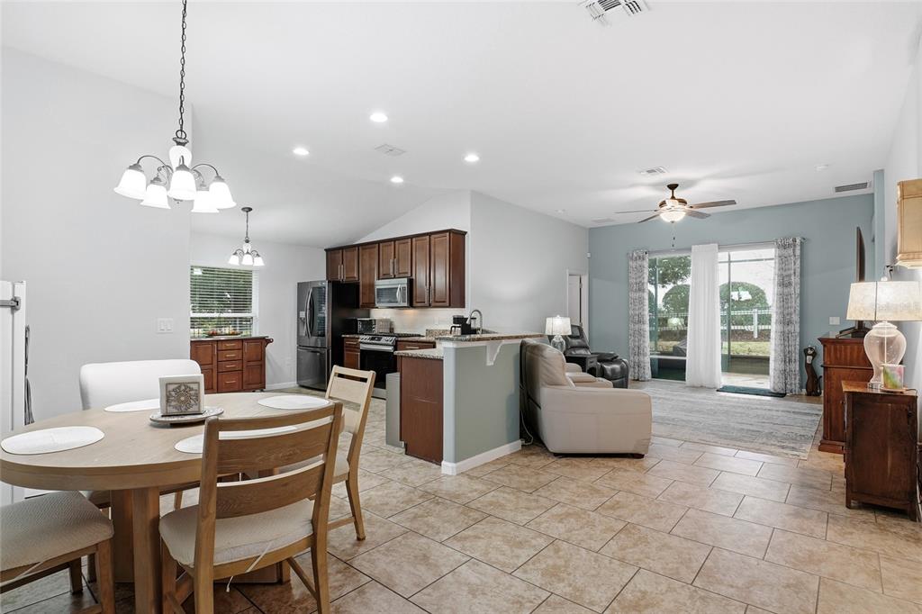 An open-concept kitchen and living area with tile floors, dark wood cabinets, and sliding doors — 476 SAUVIGNON WAY, GROVELAND, FL