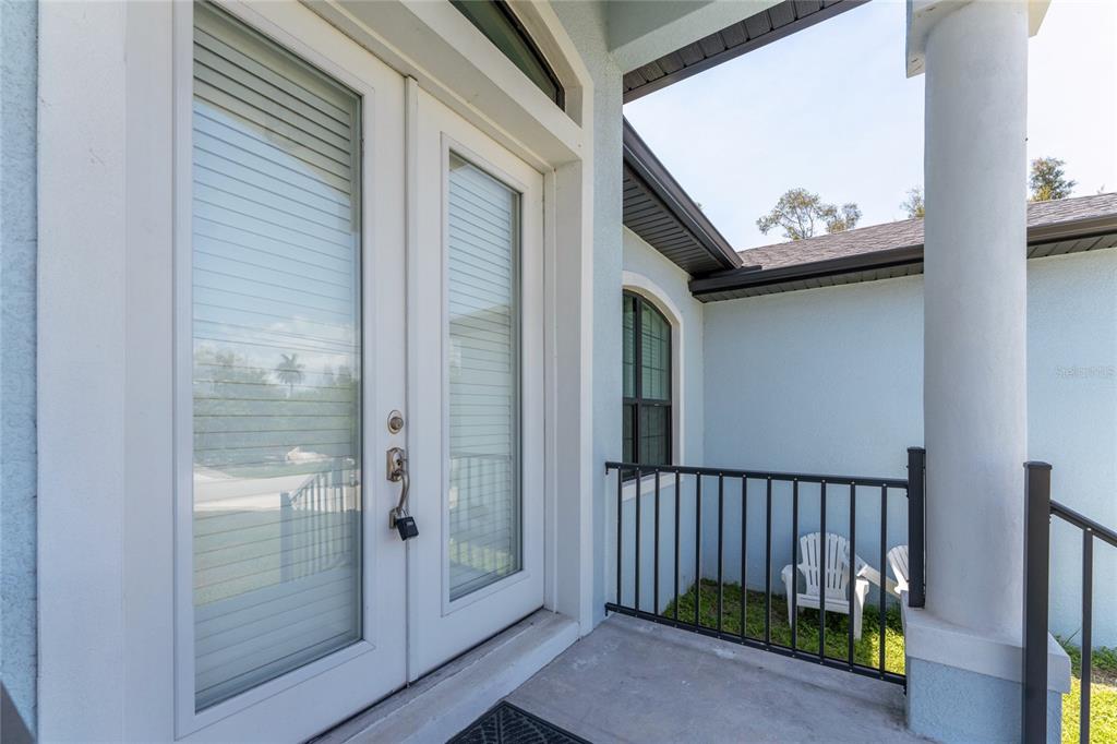 A covered entryway features double glass doors with blinds and a black metal railing — 3900 PALM DRIVE, PUNTA GORDA, FL
