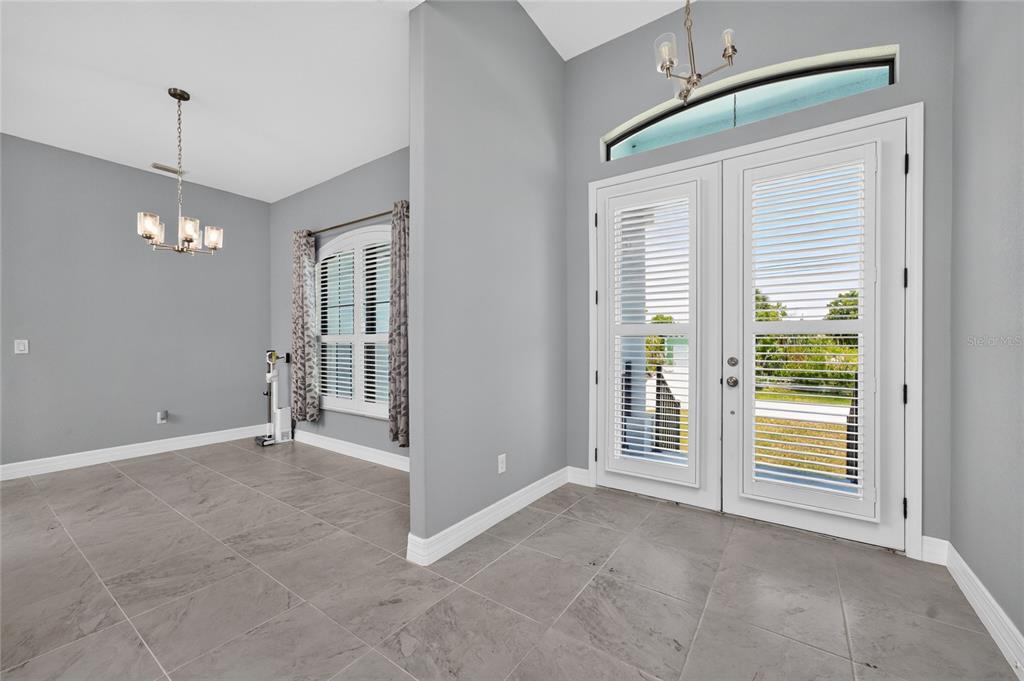 A dining area with gray tile floors and a chandelier opens to a glass-paned door — 3900 PALM DRIVE, PUNTA GORDA, FL