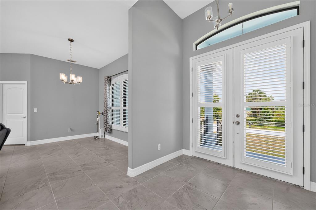 A tiled entryway with double glass doors leads into a dining area with gray walls — 3900 PALM DRIVE, PUNTA GORDA, FL