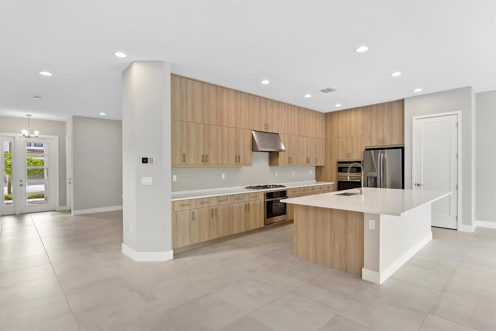 A modern kitchen features light wood cabinetry, a white quartz island, and stainless steel appliances — 20318 Castle Stuart Avenue, Boca Raton FL 33434, BOCA RATON, FL
