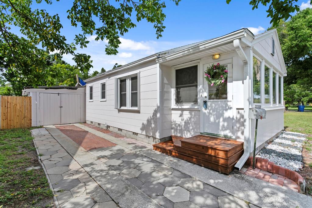 The exterior of a white house features a sunroom with large windows and a fence — 3152 13TH AVENUE N, ST PETERSBURG, FL