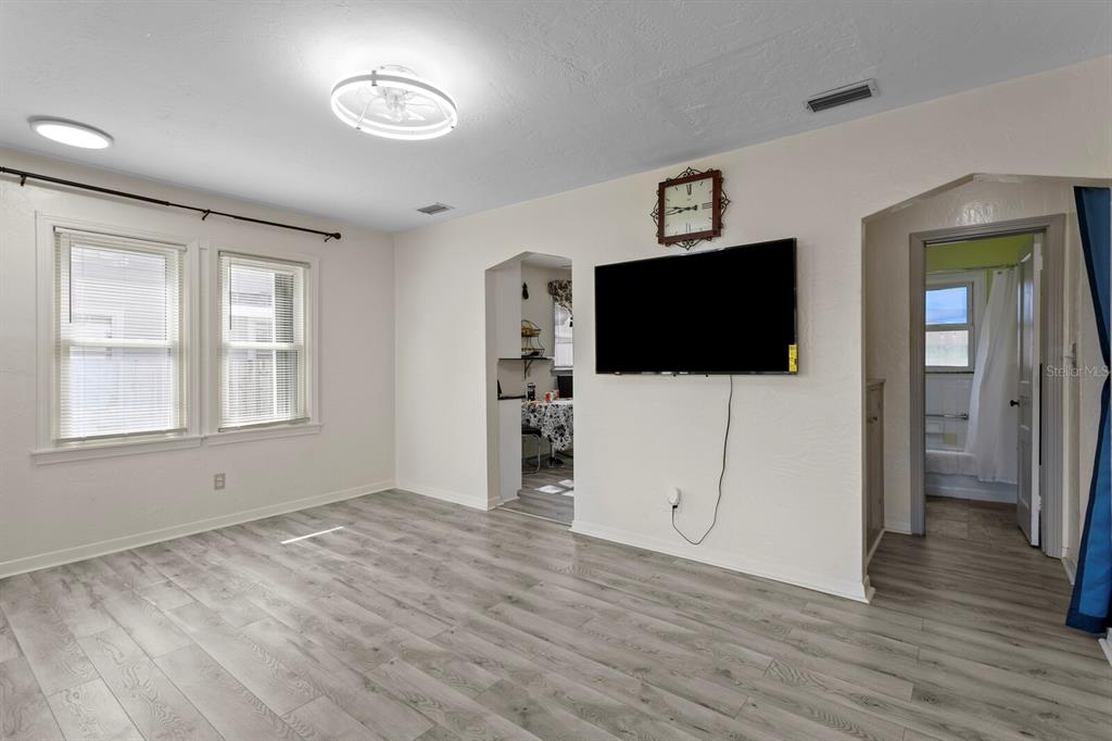 A sunroom with wood-paneled walls and ceiling opens into a living room with light flooring — 3152 13TH AVENUE N, ST PETERSBURG, FL
