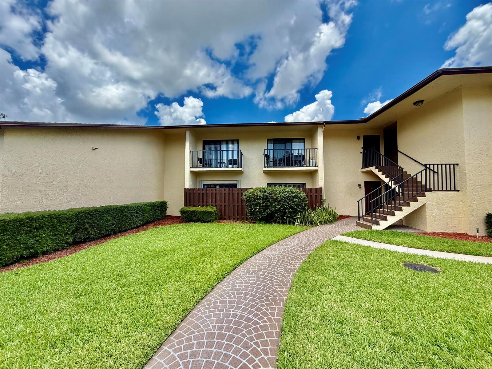 A two-story apartment building with a paved walkway, green lawn, and exterior staircase — 2050 Oleander Boulevard # 103, Fort Pierce FL 34950, FORT PIERCE, FL