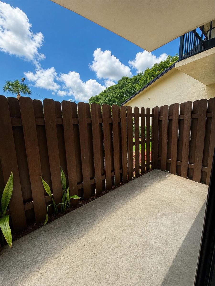 A small concrete patio is enclosed by a tall brown wooden privacy fence — 2050 Oleander Boulevard # 103, Fort Pierce FL 34950, FORT PIERCE, FL
