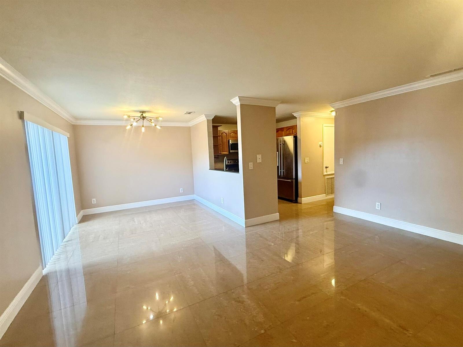 An open-concept living area features beige walls, crown molding, and polished tile flooring — 2050 Oleander Boulevard # 103, Fort Pierce FL 34950, FORT PIERCE, FL