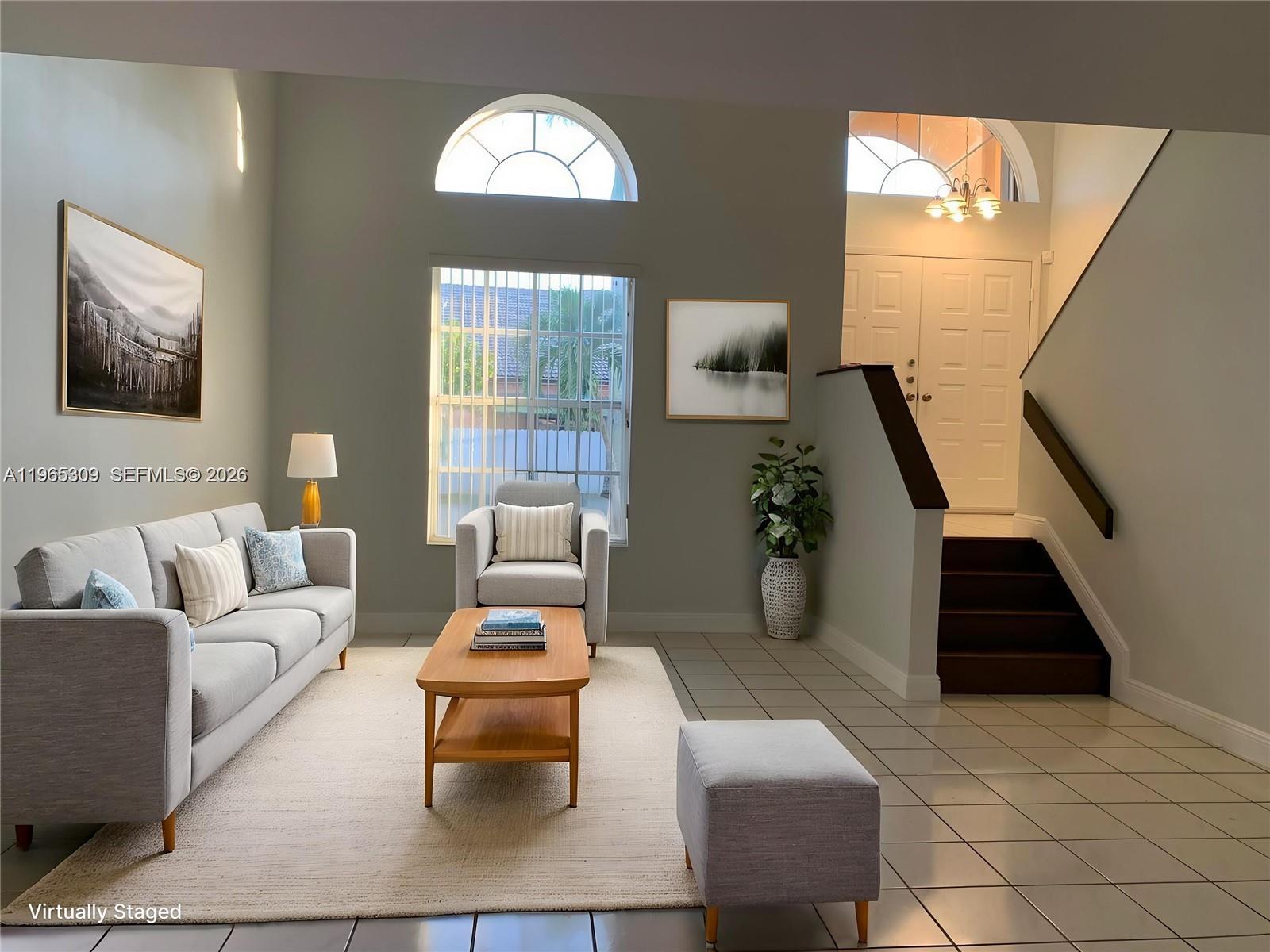 A living room features a sofa, armchair, coffee table, and stairs leading to an entryway — 12447 NW 7th St, Miami FL 33182, MIAMI, FL