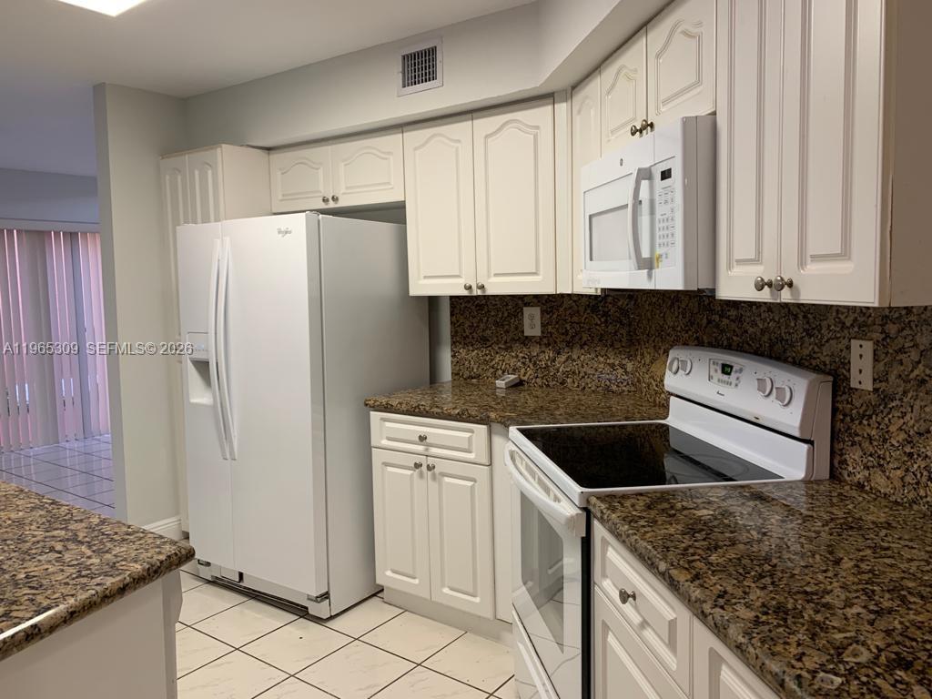 A kitchen features white cabinets, granite countertops, and white appliances — 12447 NW 7th St, Miami FL 33182, MIAMI, FL