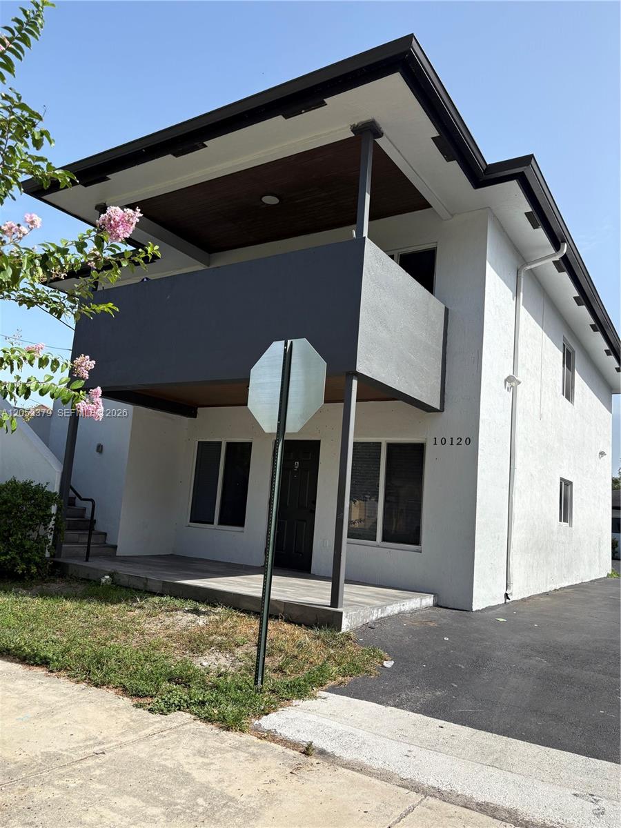 A two-story building features a dark gray balcony, white stucco walls, and a paved entrance — 10120 W Fern St, Miami FL 33157, MIAMI, FL