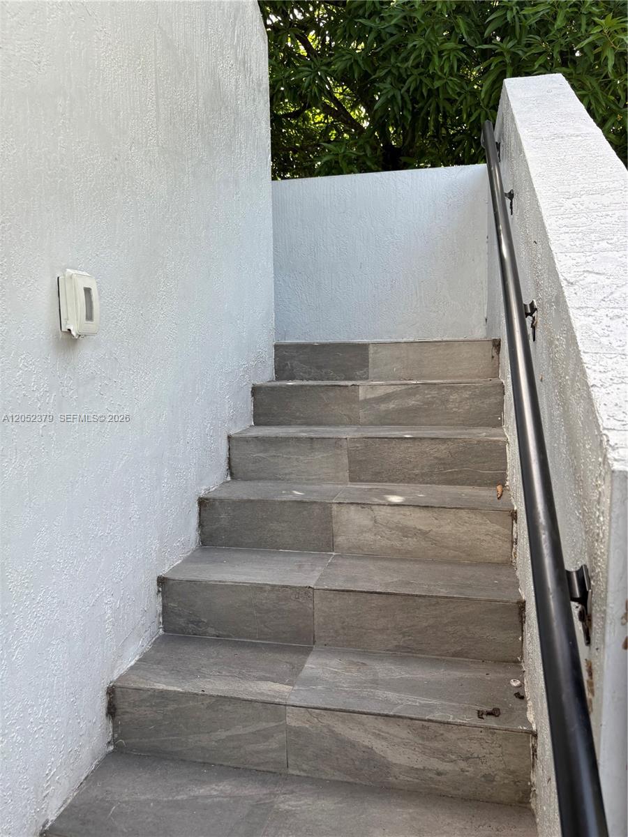 An outdoor staircase with gray tiled steps and a black metal handrail leads upward — 10120 W Fern St, Miami FL 33157, MIAMI, FL