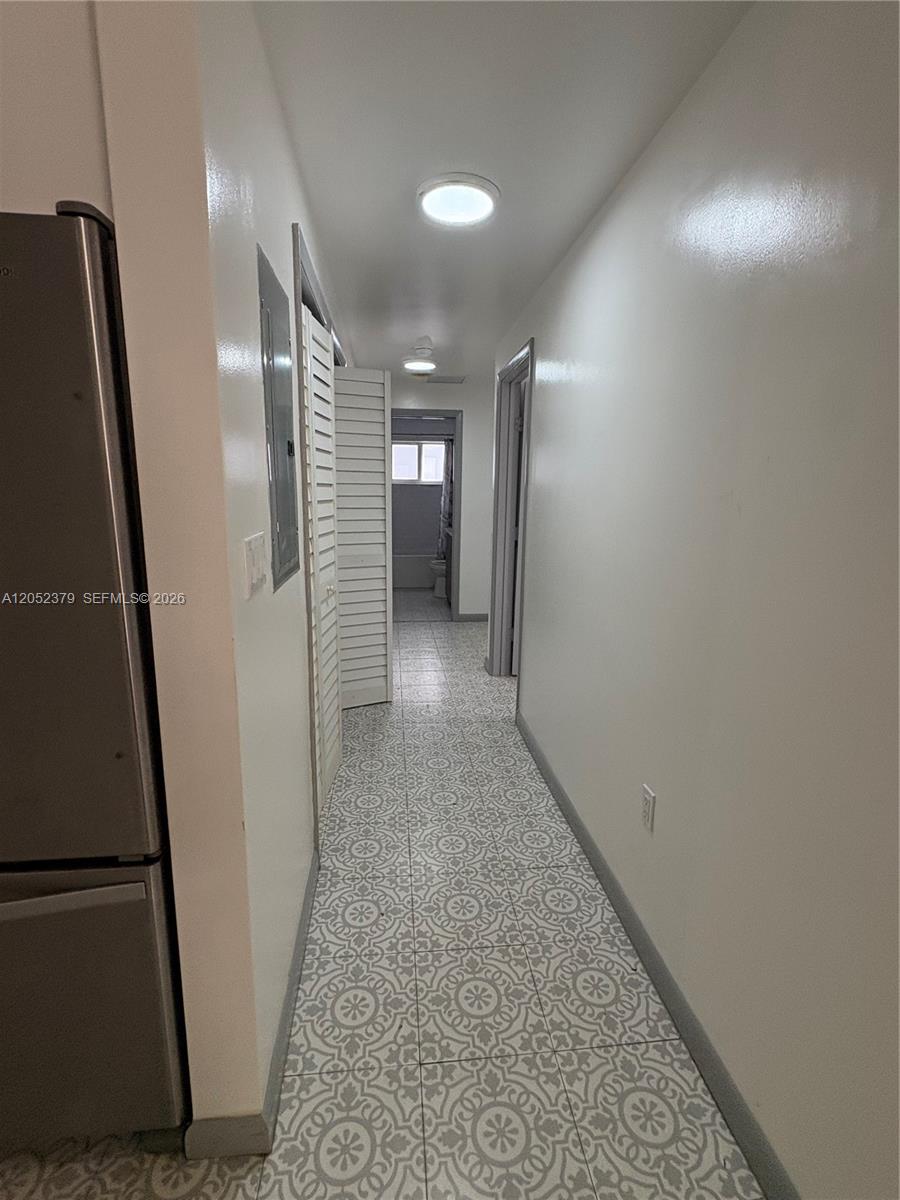 A narrow hallway features patterned tile flooring, white walls, and a recessed bathroom at the end — 10120 W Fern St, Miami FL 33157, MIAMI, FL