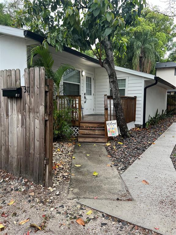 A white house exterior features a wooden deck, stairs, and a wooden privacy fence — 311 E FLORIBRASKA AVENUE UNIT A, TAMPA, FL