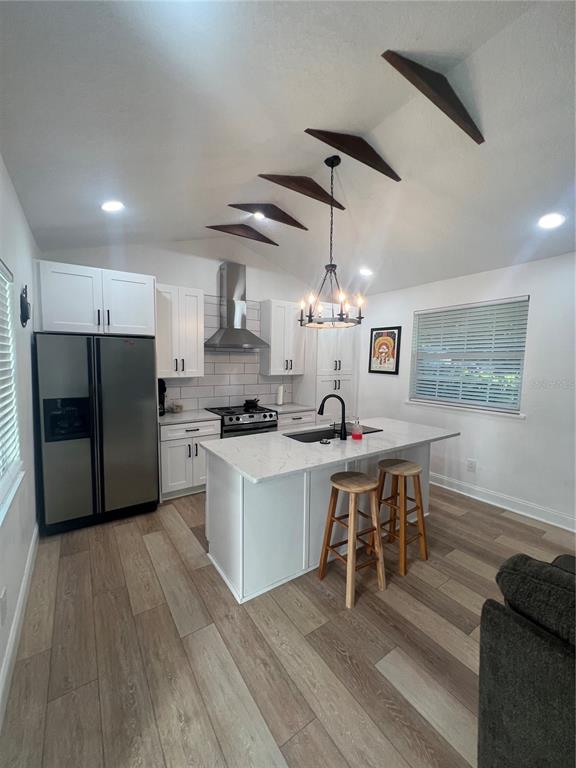 A modern kitchen features white cabinetry, a central island with bar stools, and vaulted ceilings — 311 E FLORIBRASKA AVENUE UNIT A, TAMPA, FL