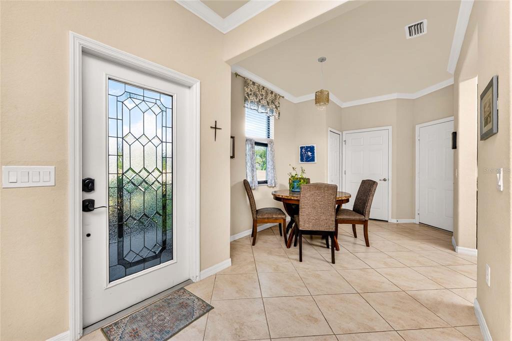 A dining area with a round table and chairs sits near a glass-paneled front door — 20133 LAGENTE CIRCLE, VENICE, FL