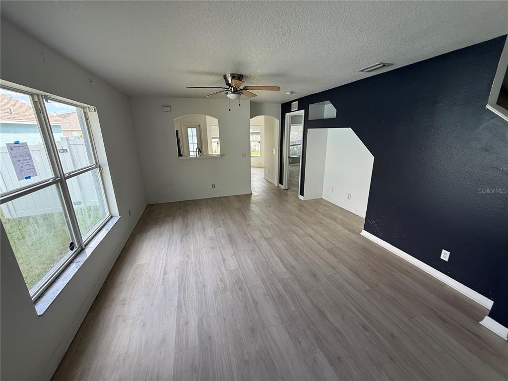 A living room features light wood-look flooring, a ceiling fan, and a dark accent wall — 4222 DAY BRIDGE PLACE UNIT 1400, ELLENTON, FL