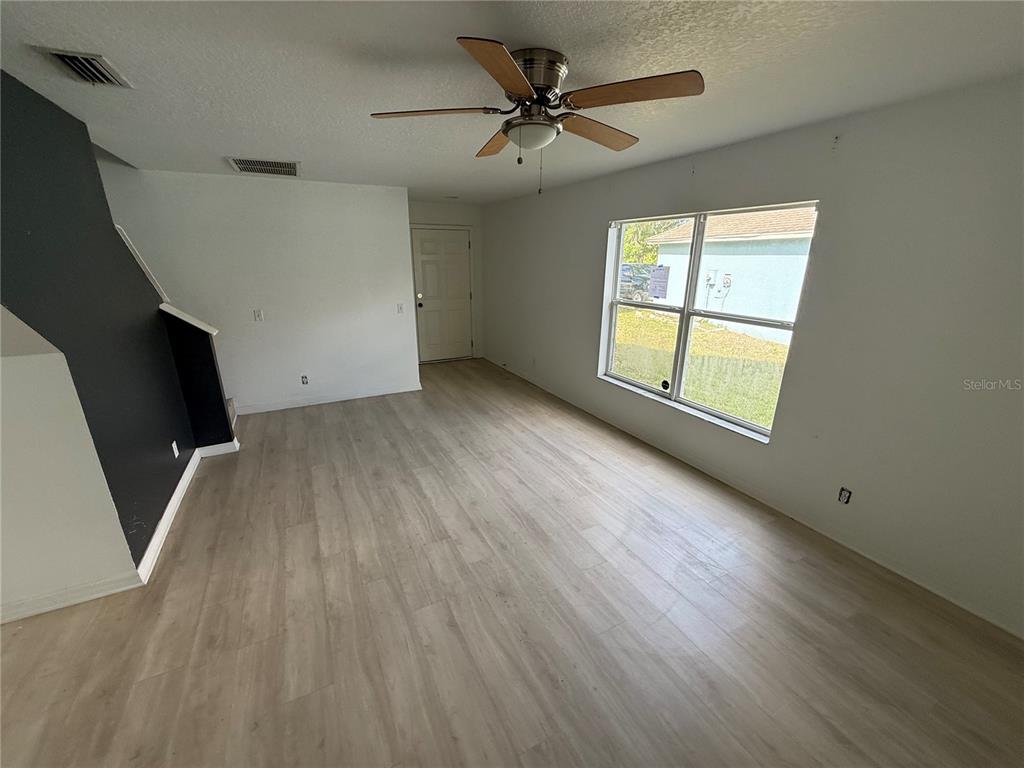 An empty room features light wood-look flooring, a ceiling fan, and a dark accent wall — 4222 DAY BRIDGE PLACE UNIT 1400, ELLENTON, FL
