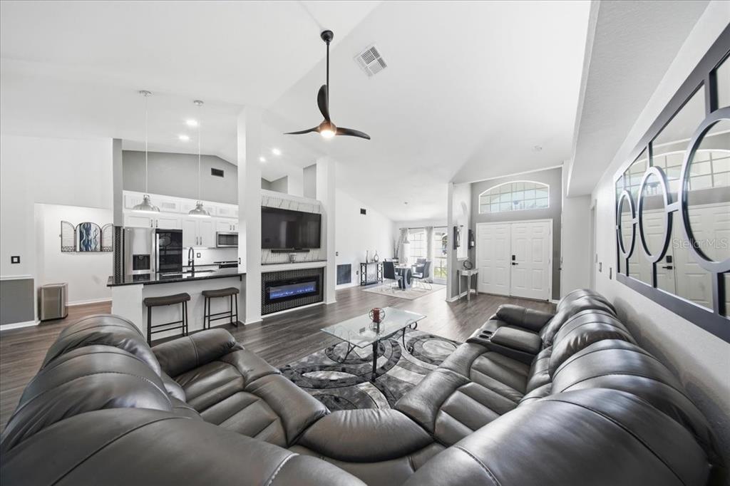 A spacious open-concept living room features a large sectional sofa, fireplace, and kitchen area — 1003 OLD CUTLER ROAD, LAKE WALES, FL