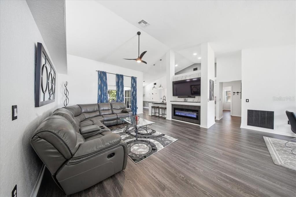 A living room with a gray sectional sofa, fireplace, television, and wood-look flooring — 1003 OLD CUTLER ROAD, LAKE WALES, FL