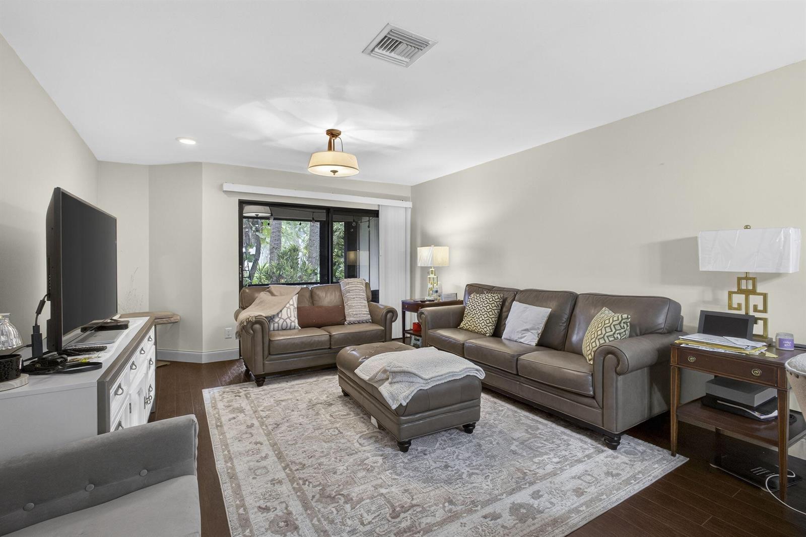 A living room features leather sofas, an ottoman, a patterned area rug, and a television — 500 Crosswinds Drive # C1, FL 33413, FL