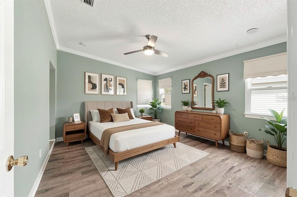 A bedroom with sage green walls, a wooden bed frame, and a matching dresser — 1401 W SCHWARTZ BOULEVARD, LADY LAKE, FL