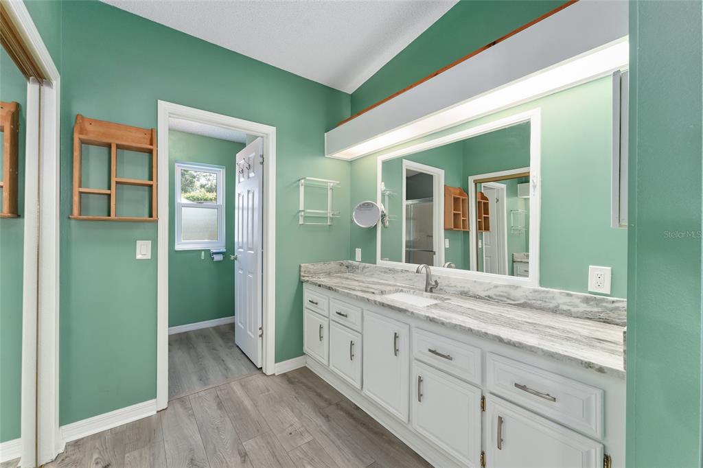 A bathroom features a long white vanity with a marble countertop and green walls — 1401 W SCHWARTZ BOULEVARD, LADY LAKE, FL