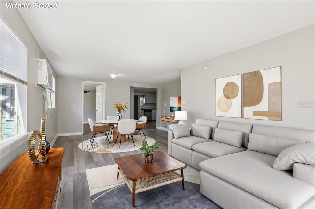 A living room with gray flooring, a sectional sofa, a dining area, and neutral walls — 2010 E YUKON STREET, TAMPA, FL