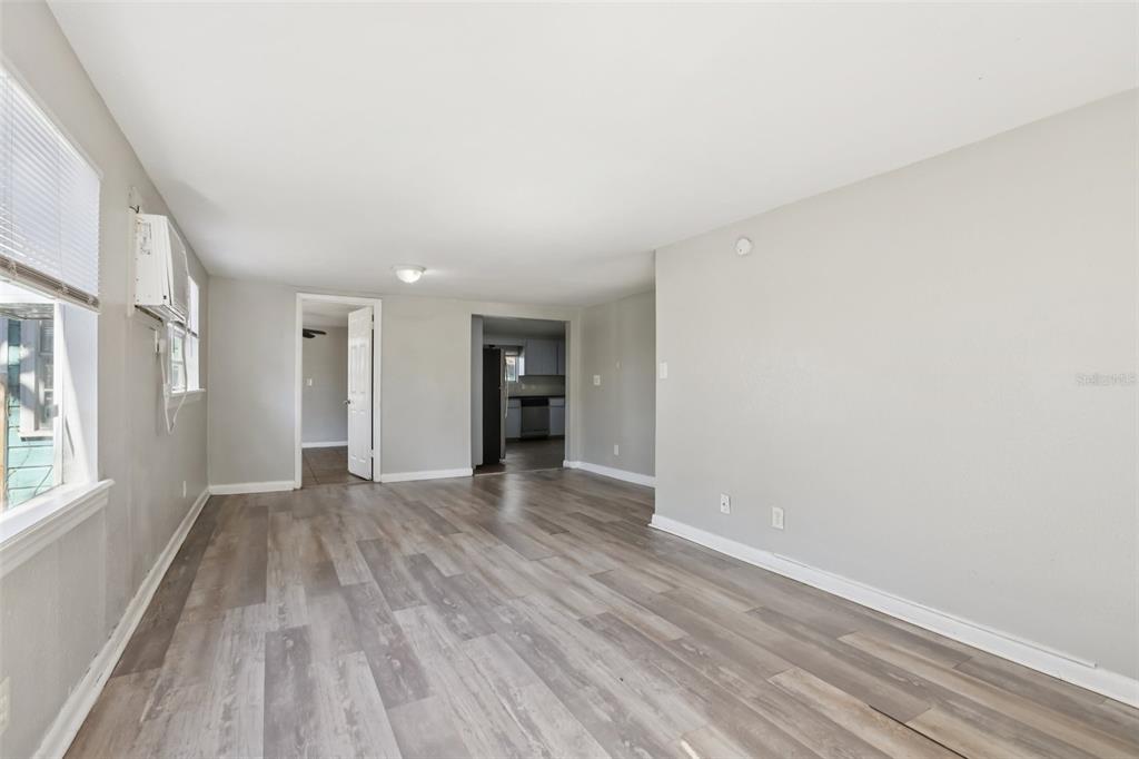 A living room with light gray walls, wood-look flooring, and a view into the kitchen — 2010 E YUKON STREET, TAMPA, FL