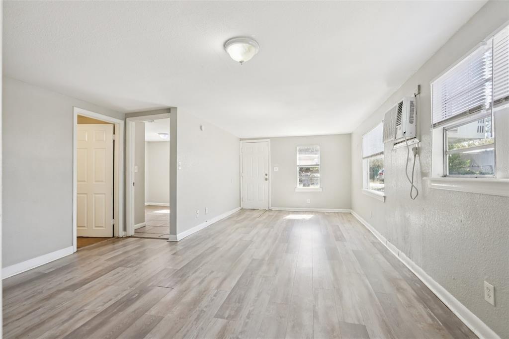 An empty room with light gray walls, wood-look flooring, a window air conditioner, and two doorways — 2010 E YUKON STREET, TAMPA, FL