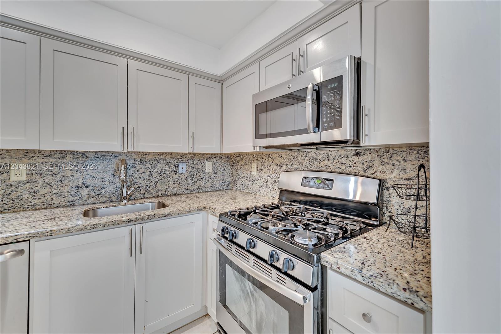 A kitchen features light gray cabinets, granite countertops, and stainless steel appliances — 1205 Mariposa Ave # 307, Coral Gables FL 33146, CORAL GABLES, FL