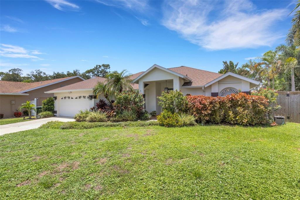 A single-story house with a white garage, a covered entryway, and a landscaped front yard — 2426 ICECAPADE DRIVE, SARASOTA, FL