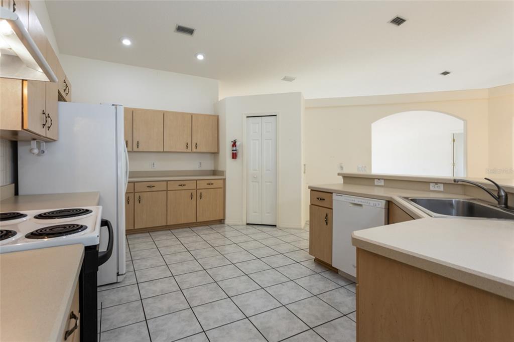A kitchen with light wood cabinets, white appliances, tile flooring, and a breakfast bar — 38 PITTWICK LANE, PALM COAST, FL