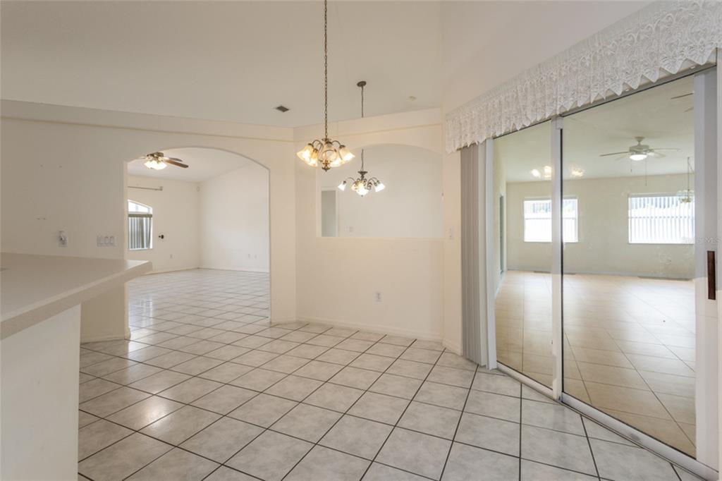 A dining area with tile floors, two chandeliers, and a sliding glass door to a patio — 38 PITTWICK LANE, PALM COAST, FL