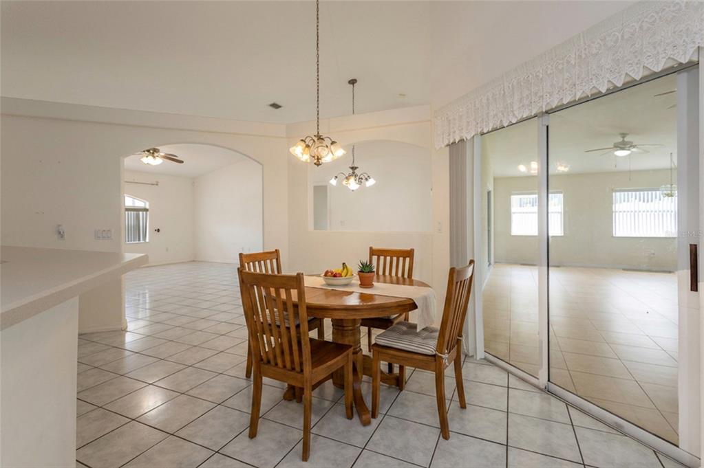 A dining area with a wooden table, four chairs, tile floors, and sliding glass doors — 38 PITTWICK LANE, PALM COAST, FL