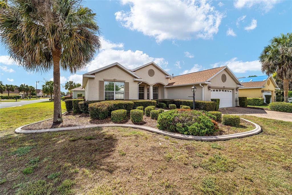 A single-story suburban house with a tan stucco exterior, a two-car garage, and landscaped yard — 8907 SW 84TH CIRCLE, OCALA, FL