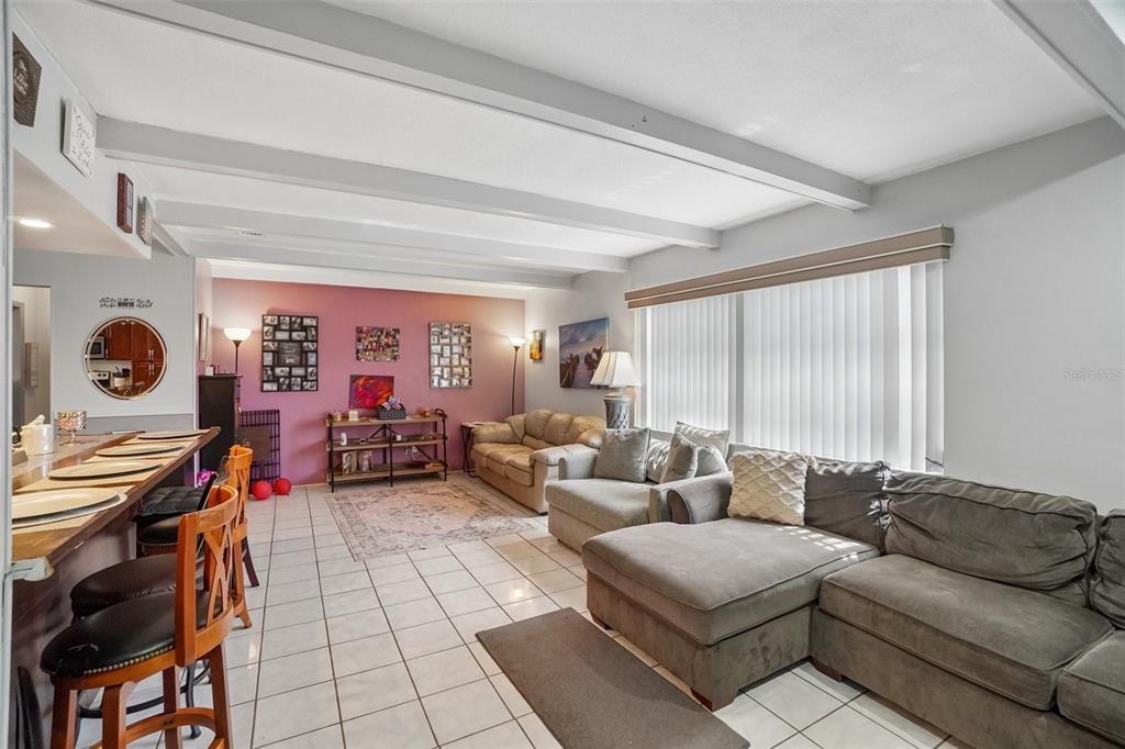 A living room features white tile floors, a vaulted ceiling with beams, and gray sectionals — 3495 OAK STREET, DUNEDIN, FL