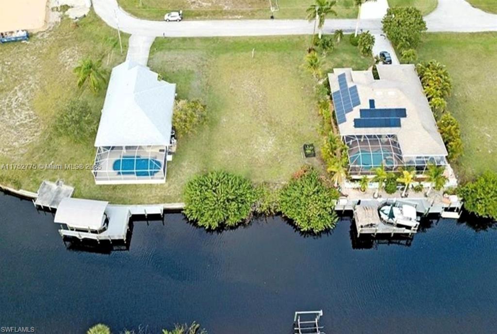 An aerial view shows two waterfront houses separated by a vacant lot along a canal — 407 NW 33rd Ave, Cape Coral FL 33993, CAPE CORAL, FL
