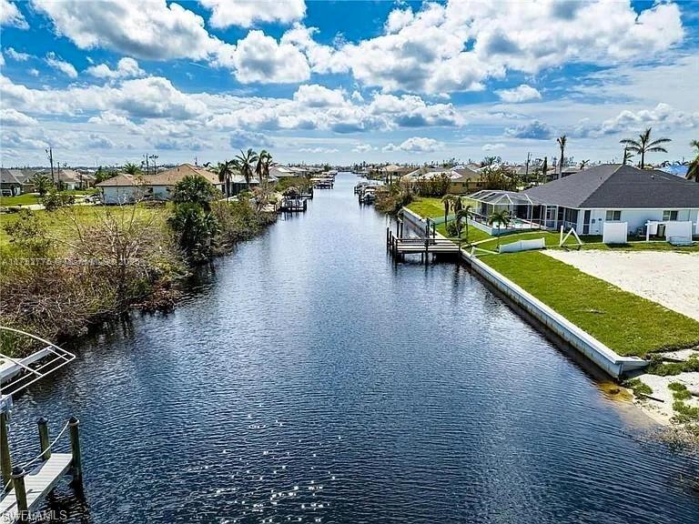 An aerial view shows a canal flowing between residential properties with docks and palm trees — 407 NW 33rd Ave, Cape Coral FL 33993, CAPE CORAL, FL