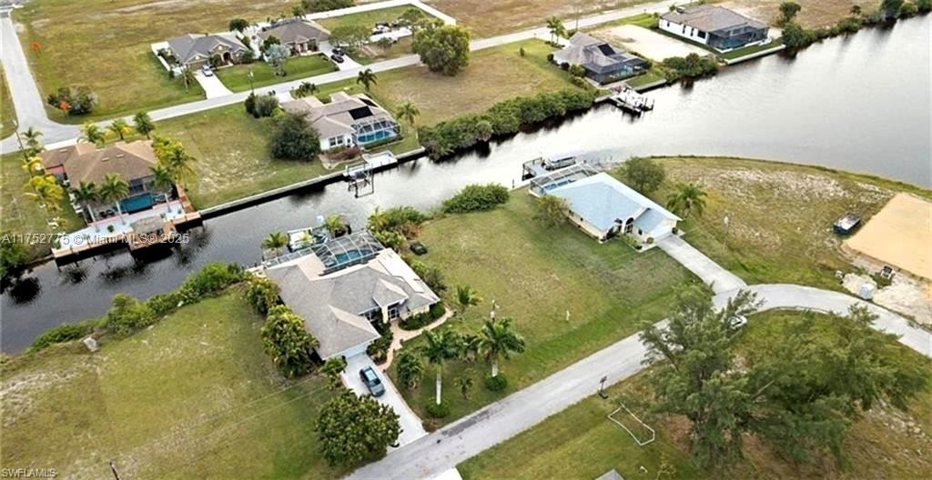 An aerial view shows several waterfront houses with pools along a canal in a residential area — 407 NW 33rd Ave, Cape Coral FL 33993, CAPE CORAL, FL