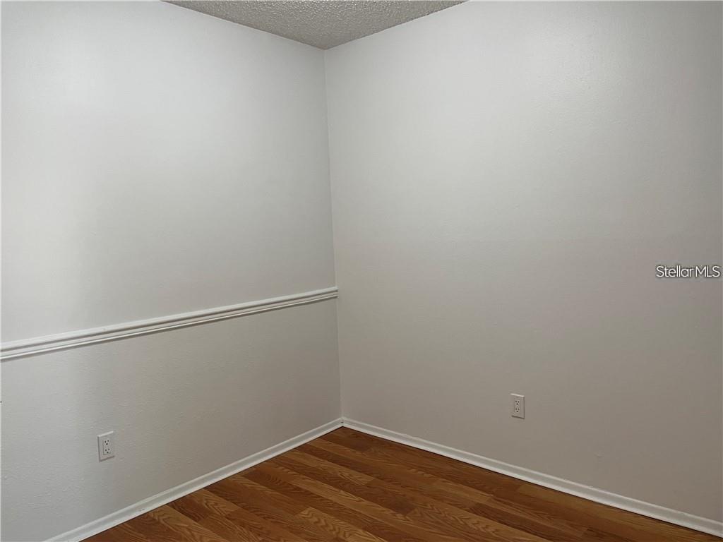 An empty room features light-colored walls with chair rail molding and wood-look flooring — 246 AFTON SQUARE UNIT 105, ALTAMONTE SPRINGS, FL