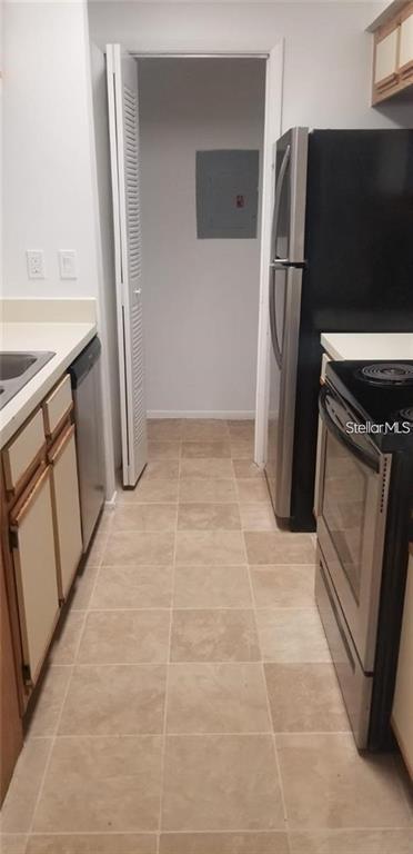 A narrow kitchen features light-colored tile flooring, white cabinets, and stainless steel appliances — 246 AFTON SQUARE UNIT 105, ALTAMONTE SPRINGS, FL