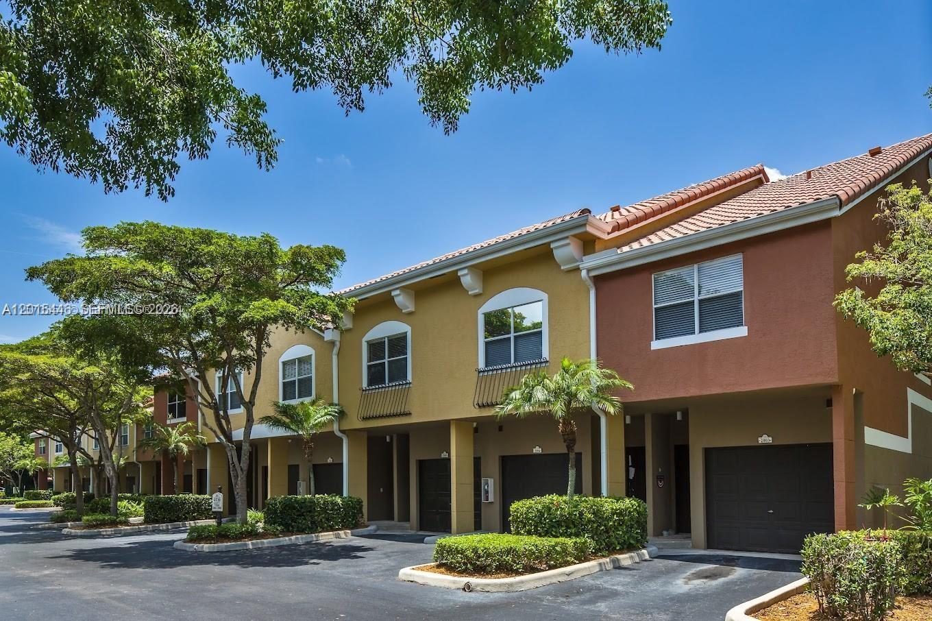 A row of multi-story townhomes with garages, stucco facades, and tile roofs under a blue sky — 5555 N Military Trl, Boca Raton FL 33496, BOCA RATON, FL