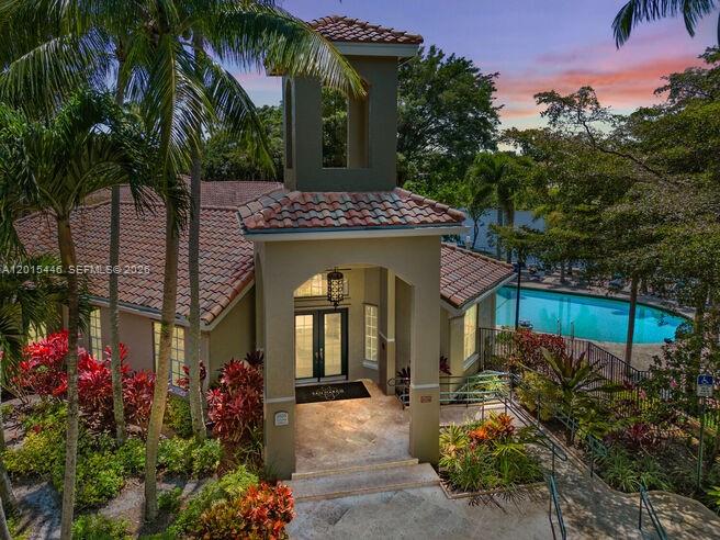 An exterior view of a building with a tiled roof, tower, and adjacent swimming pool — 5555 N Military Trl, Boca Raton FL 33496, BOCA RATON, FL