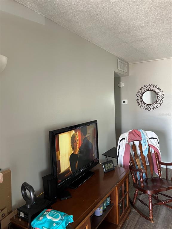 A living room features a television on a wooden stand, a rocking chair, and a mirror — 800 N FISKE BOULEVARD UNIT 506, COCOA, FL