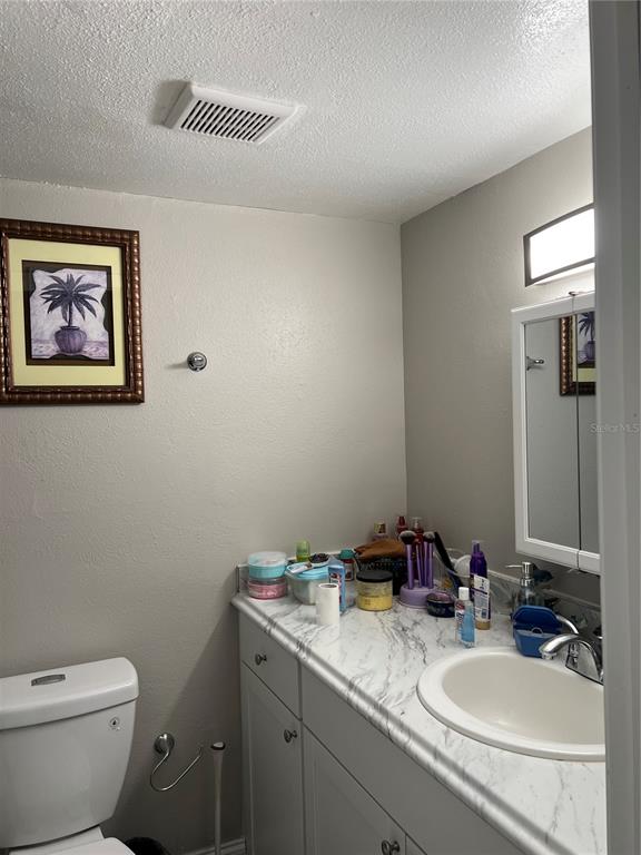 A bathroom features a white vanity with a marble-look countertop, a sink, and a toilet — 800 N FISKE BOULEVARD UNIT 506, COCOA, FL