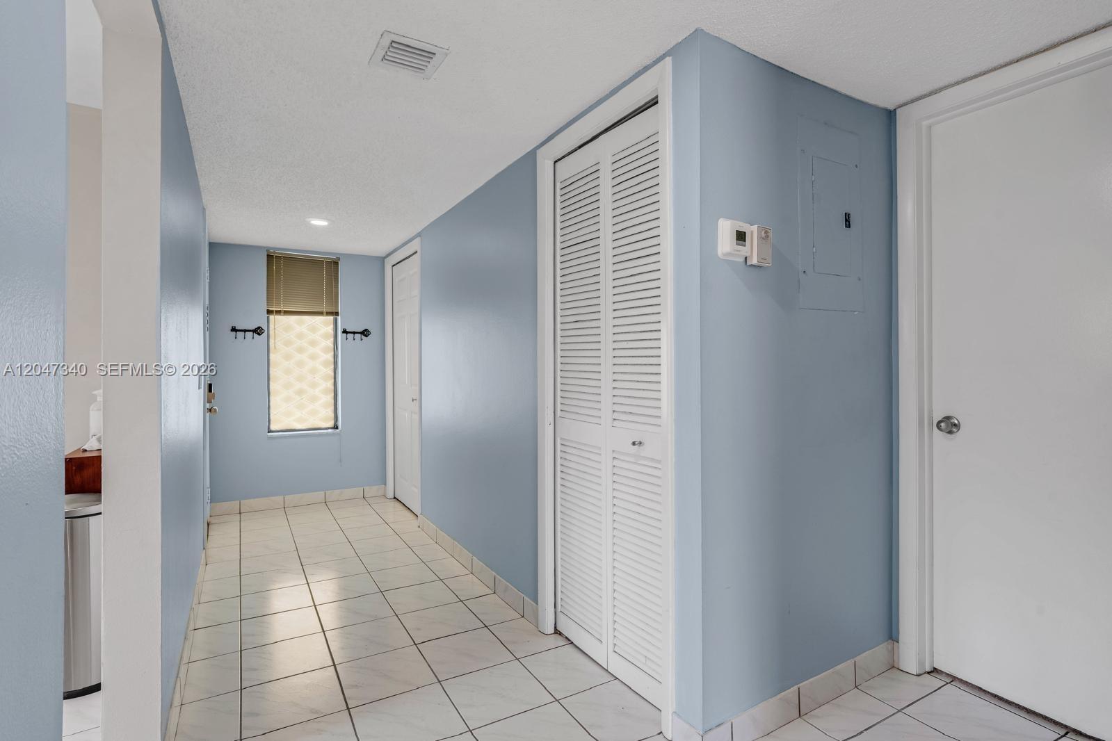 A hallway with light blue walls, white tile flooring, and white louvered closet doors — 182 Lakeview Dr # 204, Weston FL 33326, WESTON, FL