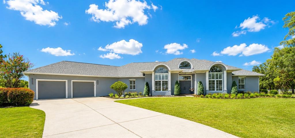 A gray single-story house with a two-car garage and a large concrete driveway — 10516 SW 27TH AVENUE, OCALA, FL