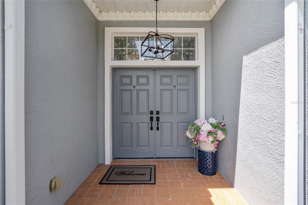 A gray double front door with a transom window sits on a brick porch — 10516 SW 27TH AVENUE, OCALA, FL