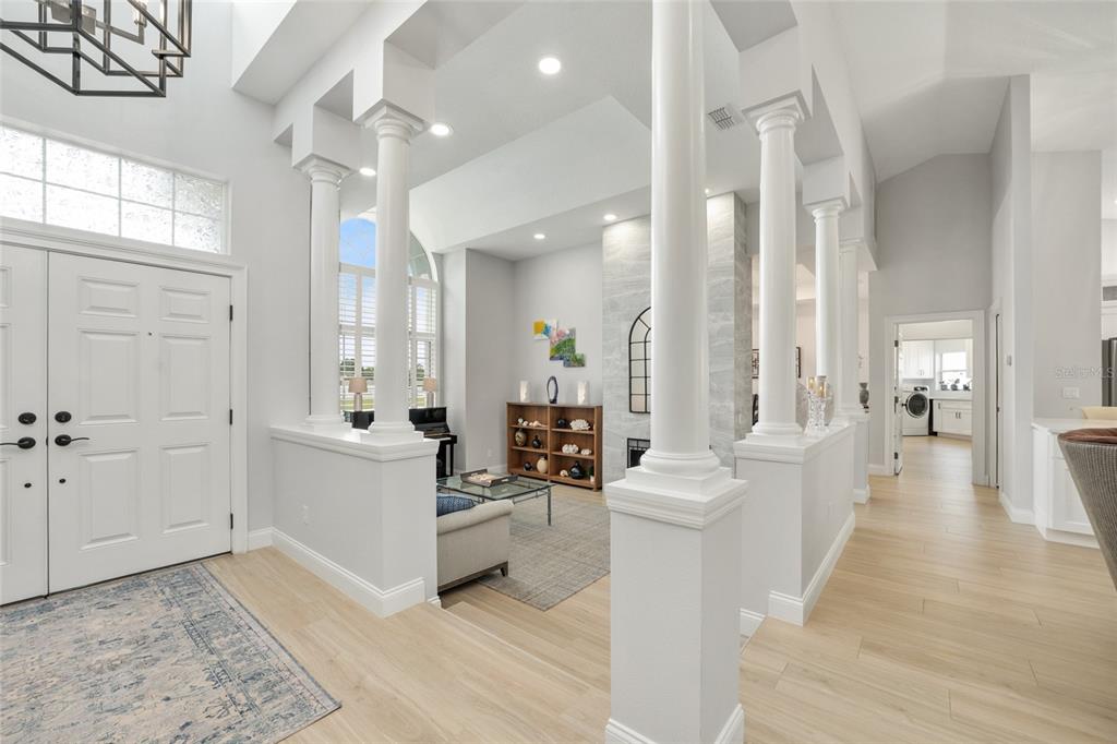 A bright, open-concept entryway leads into a living room featuring white columns and light flooring — 10516 SW 27TH AVENUE, OCALA, FL